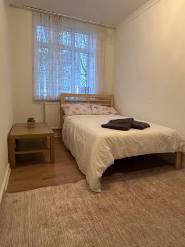 a bedroom with a bed and a table and a window at Spacious Private Room in the heart of Dalston, Hackney in London