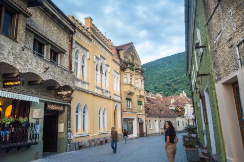 a woman walking down a street in a town at Aki Apartment in Braşov