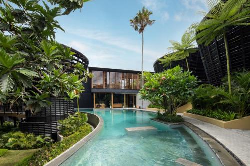 a swimming pool in the middle of a building with trees at Canggu Cabana Resort By Ini Vie Hospitality in Canggu
