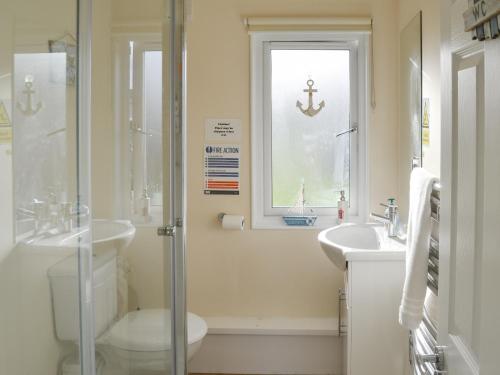 a bathroom with a sink and a toilet and a window at Roses Place in Bacton