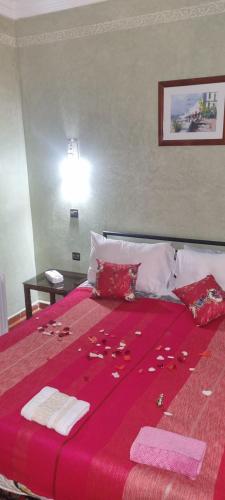 a bedroom with a bed with a red bedspread with rose petals on it at RIAD GREEN LOTUS in Marrakech