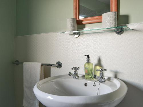 a bathroom sink with a mirror and a bottle of soap at Eleven Diabaig Cottage in Dibaig