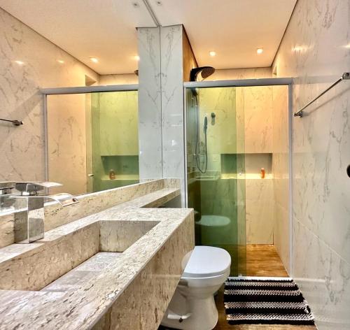 a bathroom with a toilet and a glass shower at Ap Moderno com vista mar Piscina Ar Condicionado no Guarujá in Guarujá