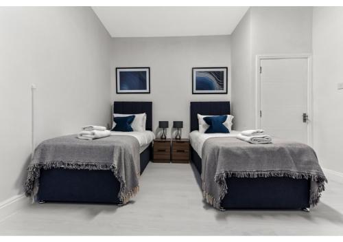 two beds in a white room with blue pillows at Captivating 2 BD Flat in London in London