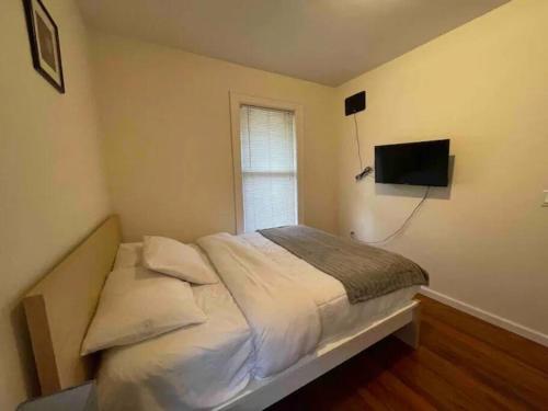 a bedroom with a bed with a television on the wall at Entire Beautiful 2BR Private Apartment [R] in Whitestone