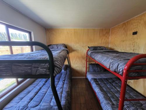 a room with three bunk beds and a window at CASA VERANEO QUILLON in Quillón