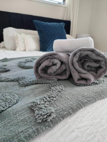 a pile of towels on top of a bed at Beautiful home near everything! in Christchurch