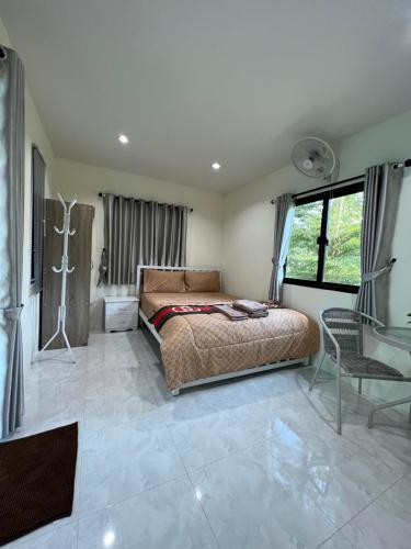 ein Schlafzimmer mit einem Bett und einem Stuhl darin in der Unterkunft Pada Guesthouse Khaoyai in Mu Si