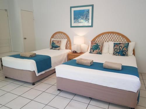 dwa łóżka w pokoju z białymi kafelkami w obiekcie Reef Suite w mieście Agnes Water
