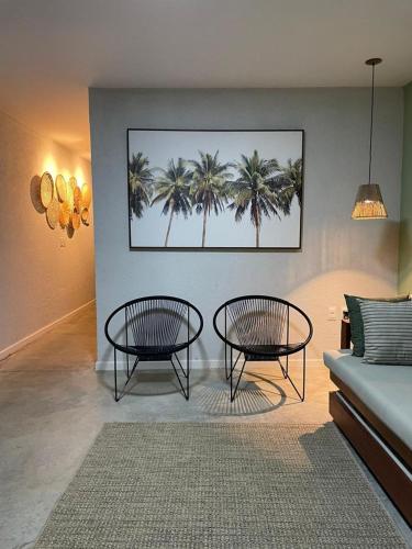 ein Wohnzimmer mit 2 Tischen und Palmen in der Unterkunft VILA CORALLI CASA 05 in Passo de Camarajibe