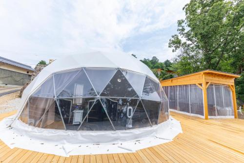 a large tent on a wooden deck with a building at グランピング　星が見の杜 in Nakatsugawa