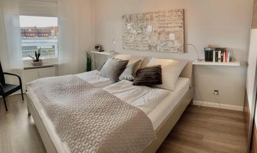 Un dormitorio con una cama grande con almohadas. en Norderhoog-Whg-38-1-OG-Wohnung-38, en Westerland