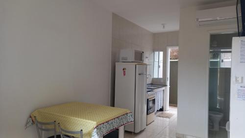 eine Küche mit einem Kühlschrank und einem Hocker darin in der Unterkunft Sol Nascente Apartamentos - Pontal do Sul in Pontal do Paraná