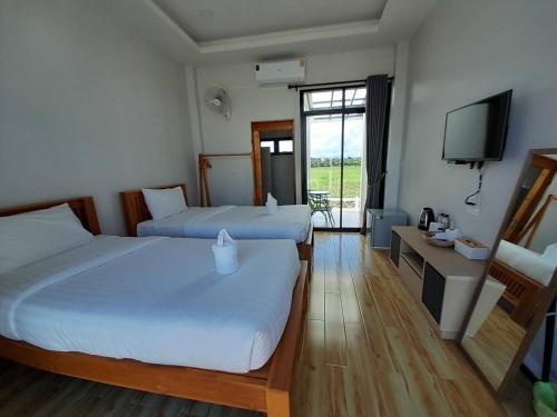 a hotel room with two beds and a television at เดอนาปัว วิลล่า in Ban Chalaeng