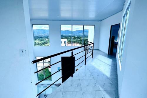 eine Treppe in einem weißen Zimmer mit großen Fenstern in der Unterkunft Buena vista Casa Quinta con Piscina y Mirador in Carmen de Apicalá