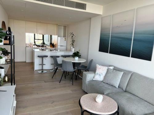 a living room with a couch and a table and a kitchen at Luxury 3 Bed 2 Bath + car park at Melbourne Square in Melbourne