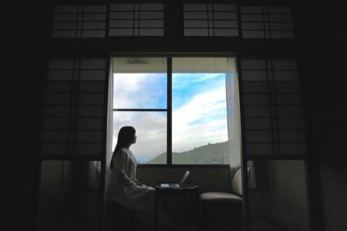a woman sitting in front of a window with a laptop at H,U,B Unzen - Vacation STAY 74185v in Unzen