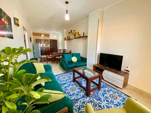Charbel apartments في الغردقة: غرفة معيشة مع أريكة زرقاء وتلفزيون