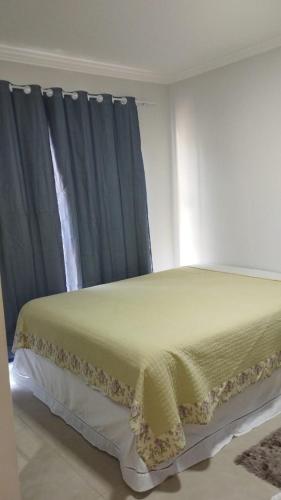 um quarto com uma cama com cortinas azuis em Suíte Deluxe em Itajaí
