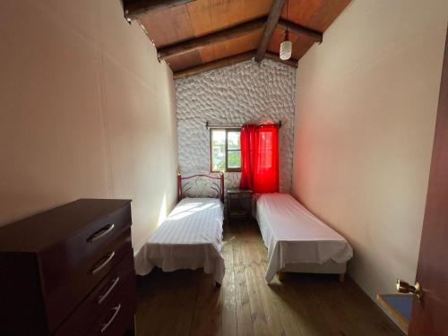 Habitación con 2 camas y ventana roja. en Casa grande los tatas, en Maldonado
