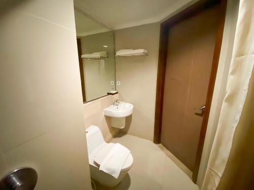 a bathroom with a toilet and a sink and a mirror at Bueno Colombo Hotel Yogyakarta in Kalasan