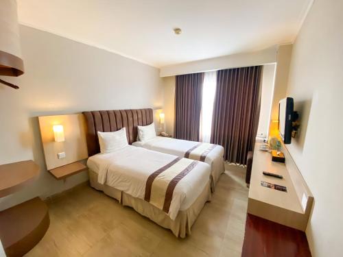 ein Hotelzimmer mit einem Bett und einem TV in der Unterkunft Bueno Colombo Hotel Yogyakarta in Kalasan