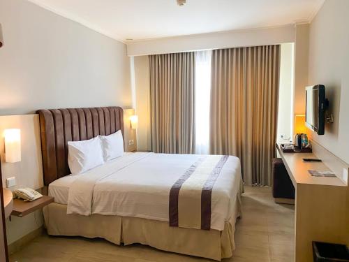 a hotel room with a bed and a television at Vrata Hotel Yogyakarta in Kalasan