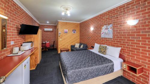 Zimmer mit einem Bett und einer Ziegelwand in der Unterkunft Elms Motor Inn in Tumut