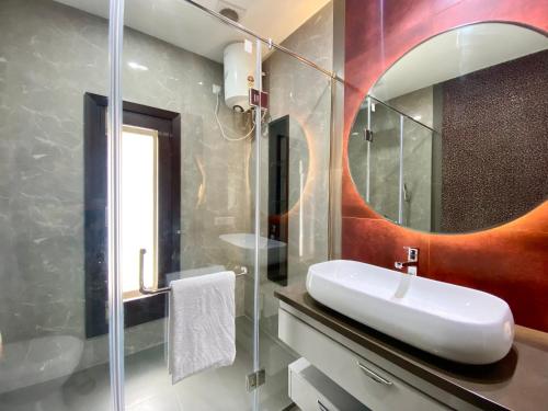 a bathroom with a white sink and a mirror at Vastu Serene Studio Apartment in Dehradun