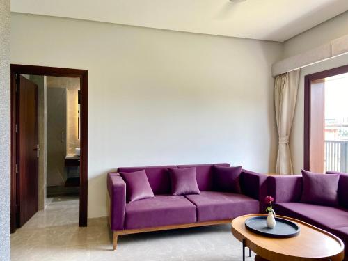 a living room with a purple couch and a table at Vastu Serene Studio Apartment in Dehradun
