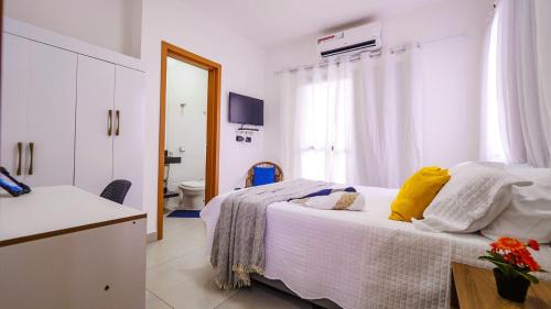 - une chambre blanche avec un lit et une salle de bains dans l'établissement Chalé Amarelo, à Itanhaém
