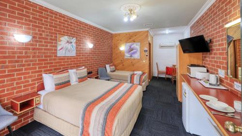 a hotel room with a bed and a brick wall at Elms Motor Inn in Tumut