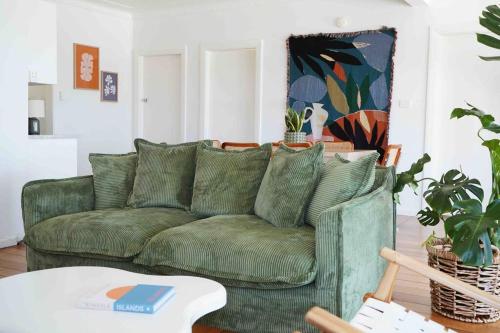 a living room with a green couch and a table at Sunset Beach House in Soldiers Point