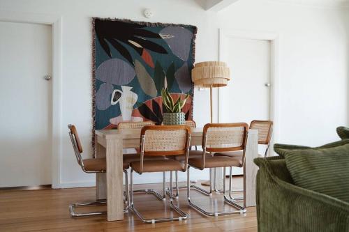 stół jadalny z krzesłami i obraz na ścianie w obiekcie Sunset Beach House w mieście Soldiers Point