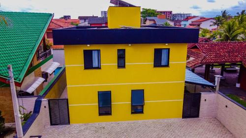 a yellow building with a blue roof in a city at Chalé Amarelo in Itanhaém