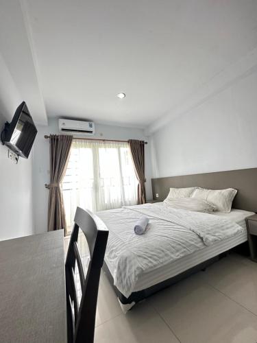 a bedroom with a bed and a table and a window at Super Deluxe Apartment with Skypool Medan in Sunggal