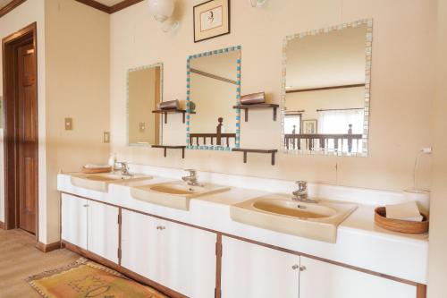 a bathroom with three sinks and two mirrors at Lodge Kent in Hokuto