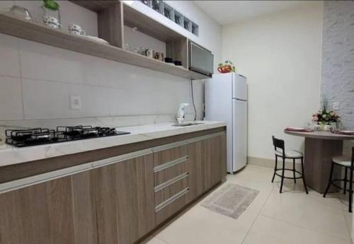 a kitchen with a sink and a refrigerator and a table at Flat Morada da Neblina! in Chapada dos Guimarães