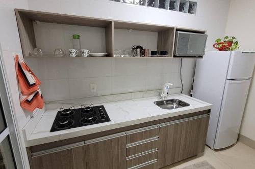 a kitchen with a stove and a sink and a refrigerator at Flat Morada da Neblina! in Chapada dos Guimarães