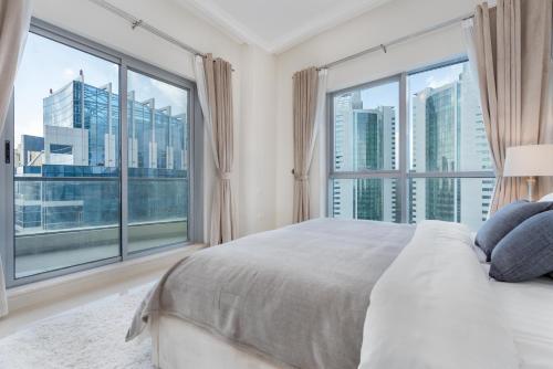 1 dormitorio con 1 cama grande y ventanas grandes en Perfect 2BD apartment in the heart of Marina - top spot, en Dubái