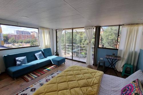 uma sala de estar com um sofá azul e janelas grandes em Aparta estudio Colorido em Bogotá
