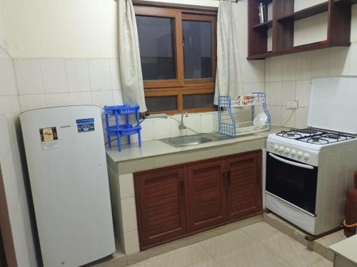 a kitchen with a white refrigerator and a stove at VEE PALACE LUXURIOUS APARTMENT - MTWAPA in Mtwapa