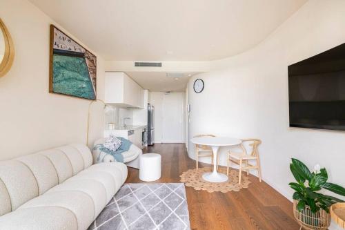 een woonkamer met een witte bank en een tafel bij Beachside flat with free parking in Melbourne