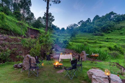 a table and chairs with a fire in a field at StayVista at Leopard's Creek with Pool in Solan
