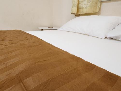 a bed with white sheets and a brown blanket at HOMEis Villa Sattahip in Ban Tao Than