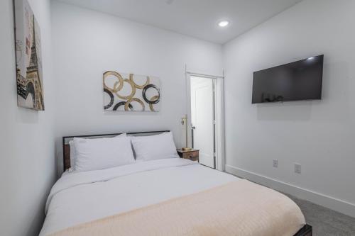 a white bedroom with a bed and a flat screen tv at Dream suite in downtown in Houston
