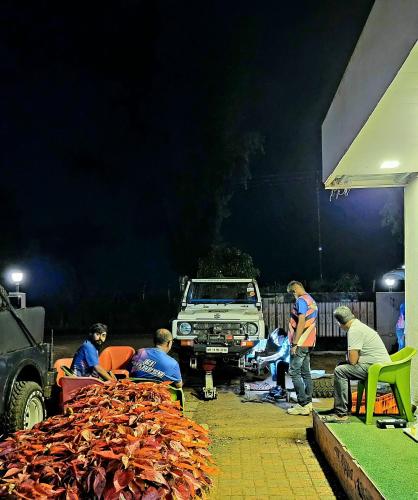 a group of people working on a car at night at Vayu Resort - Kas Pathar in Kanera