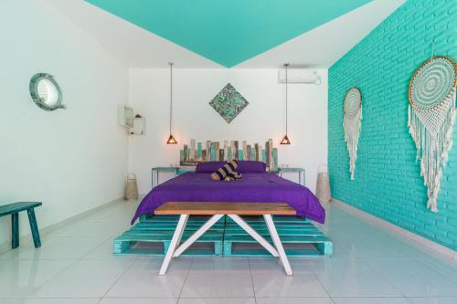 een slaapkamer met een paars bed en een blauwe muur bij Balifornia Villa Canggu in Canggu