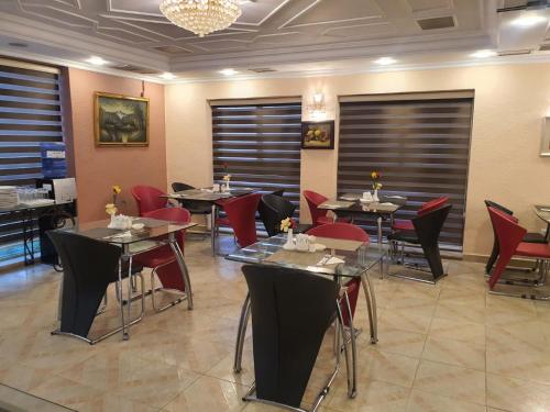 un restaurant avec des tables et des chaises et un lustre dans l'établissement Aghadeer Hotel, à Amman