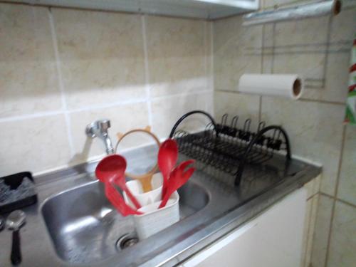 un fregadero de cocina con utensilios rojos. en apartamento en Recife